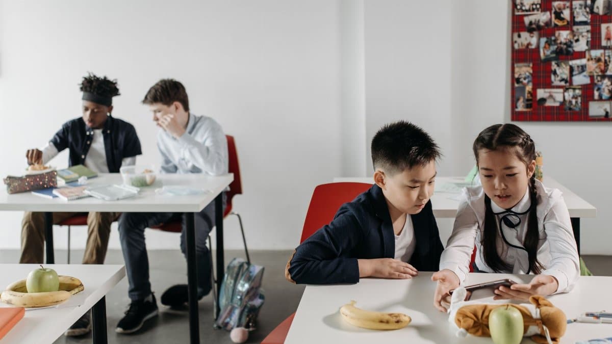 Students of various ethnicities studying and socializing in a classroom during a break.