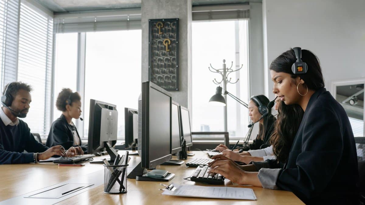 A team of call center agents working in a modern office with headsets and computers.