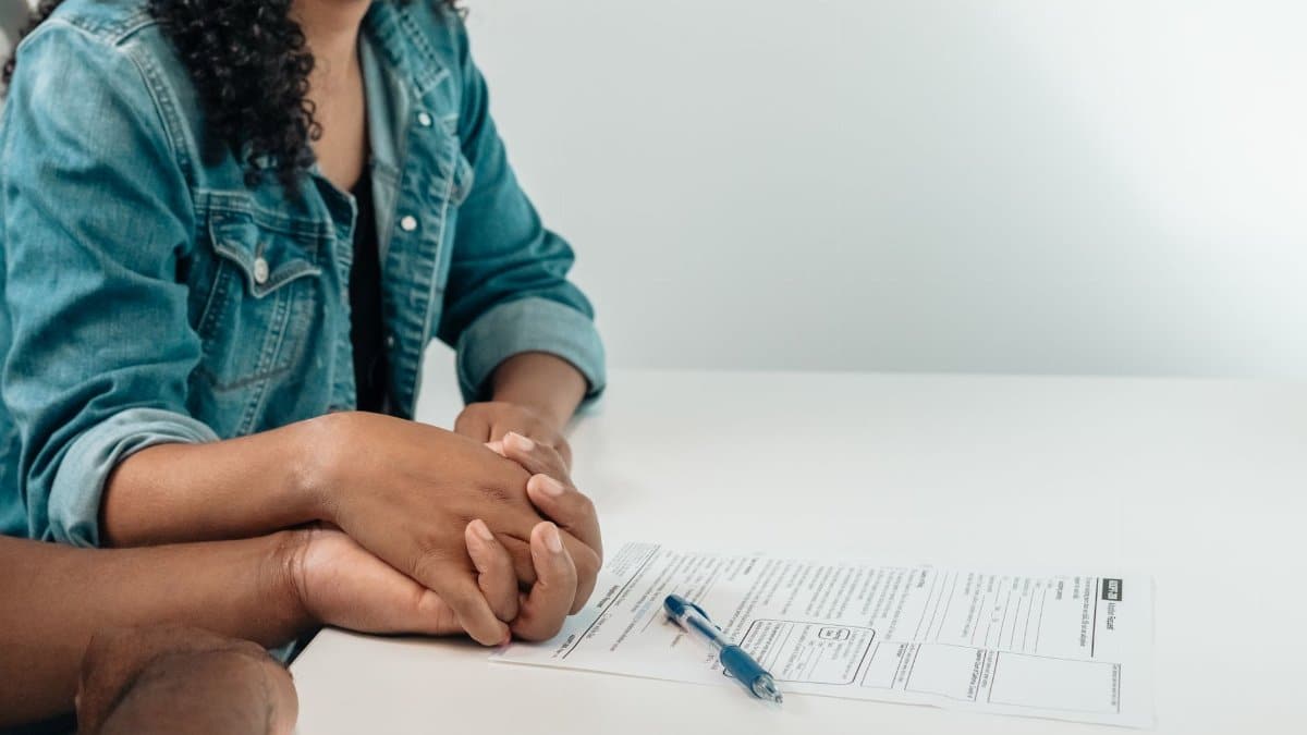 Couple holds hands over adoption papers, symbolizing family unity and support in a legal setting.
