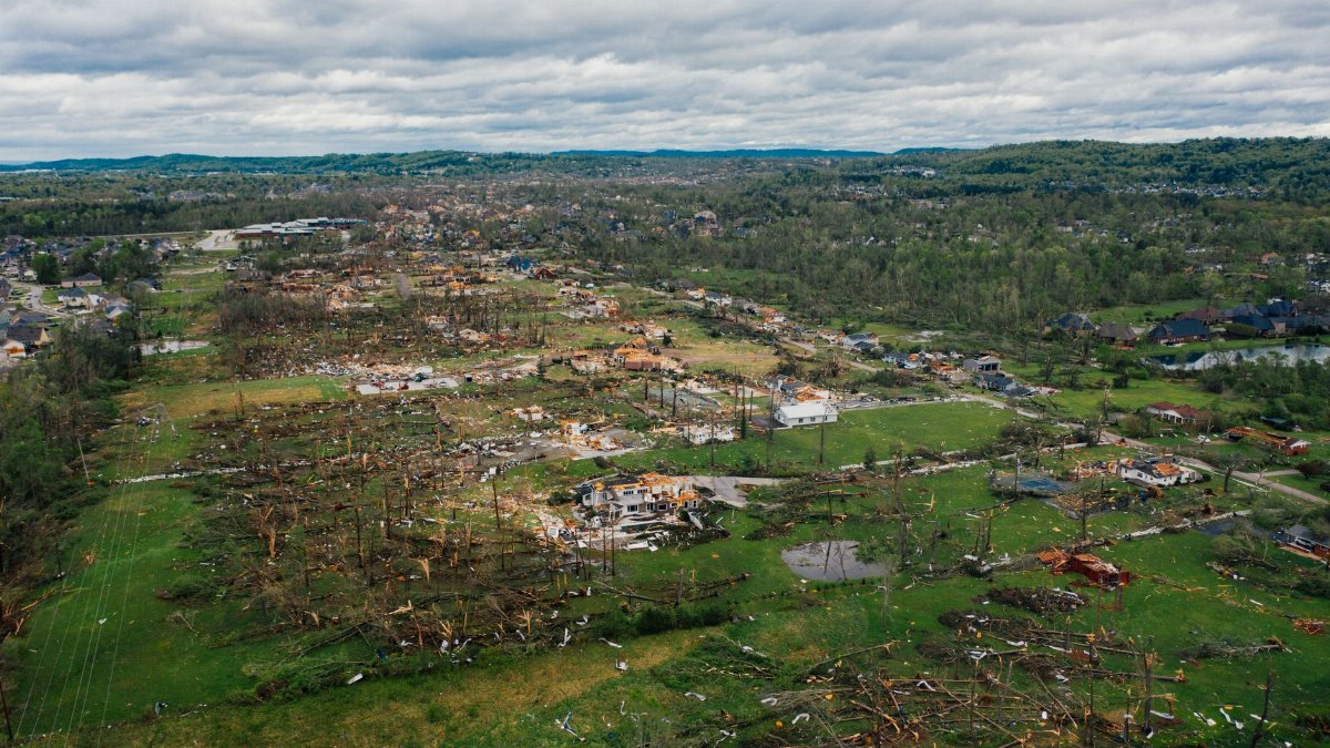 Aerial view aftereffects of massive storm on small village including windthrown bent trees and destroyed buildings