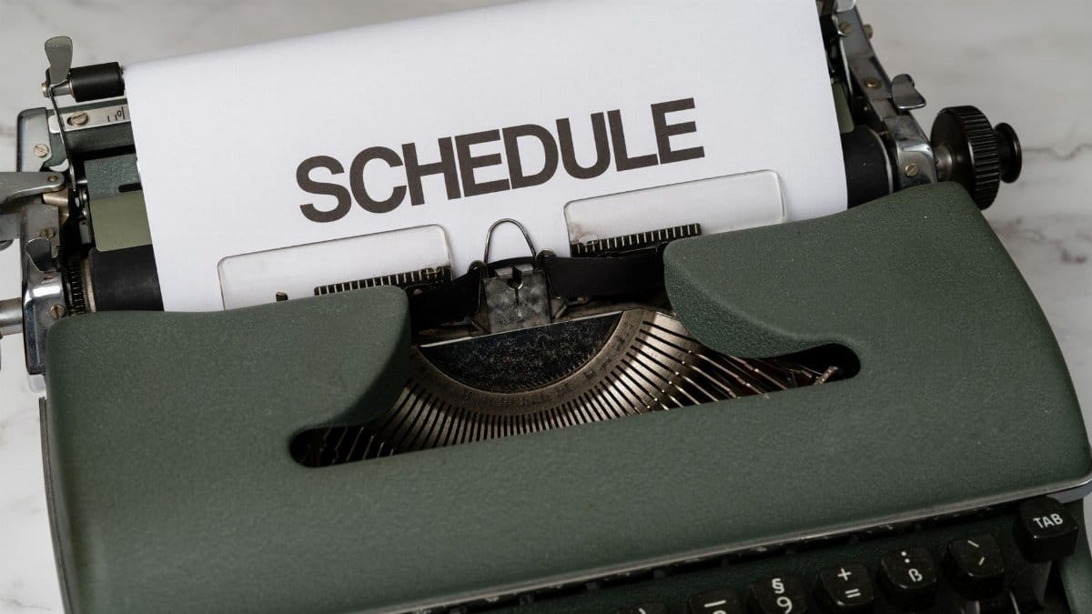 Classic vintage typewriter displaying the word 'SCHEDULE' on paper, resting on a marble surface.