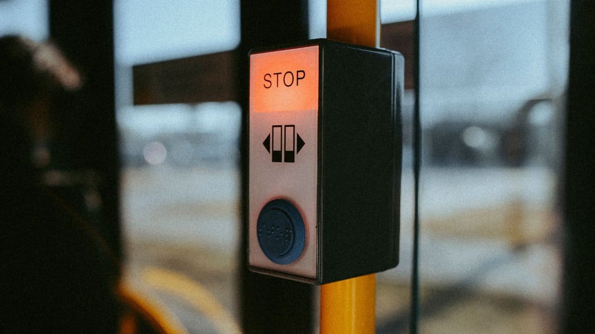 A close-up of a stop button on a public bus, highlighting travel and safety features.
