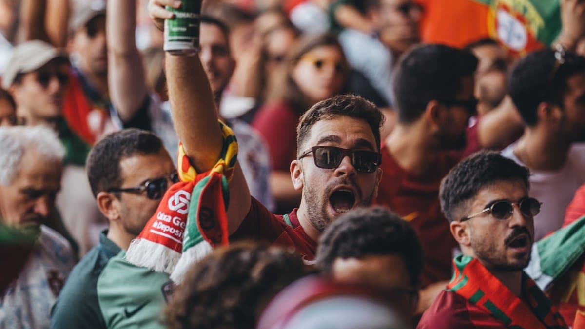 A lively crowd passionately cheering at a sports event, waving flags and enjoying the vibrant atmosphere.