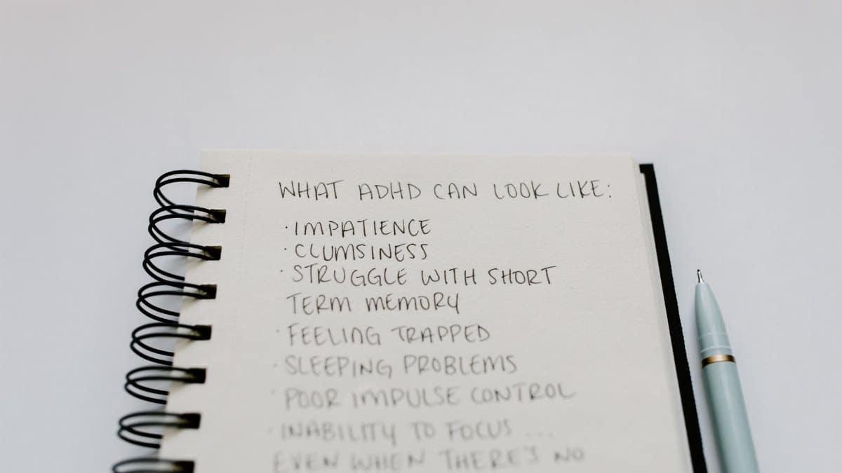 A notebook with handwritten ADHD symptoms like impatience and focus issues.