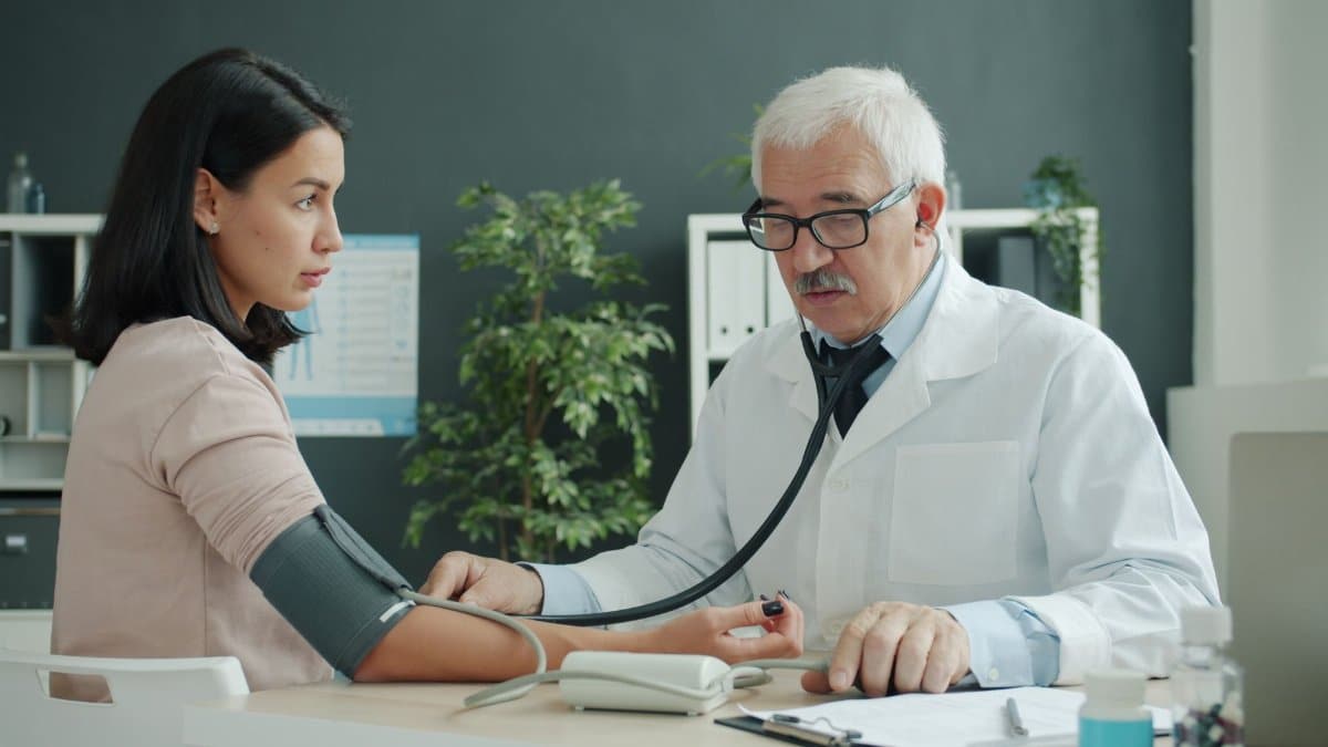 Doctor checking blood pressure of patient at medical clinic.