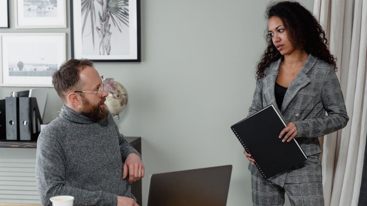 A man and woman discuss work in a stylish office environment with modern decor.