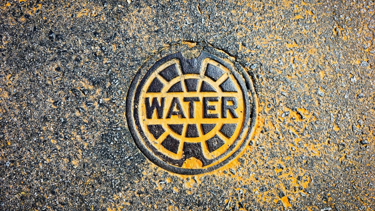 Colorful water utility cover on street pavement blends art with functionality.