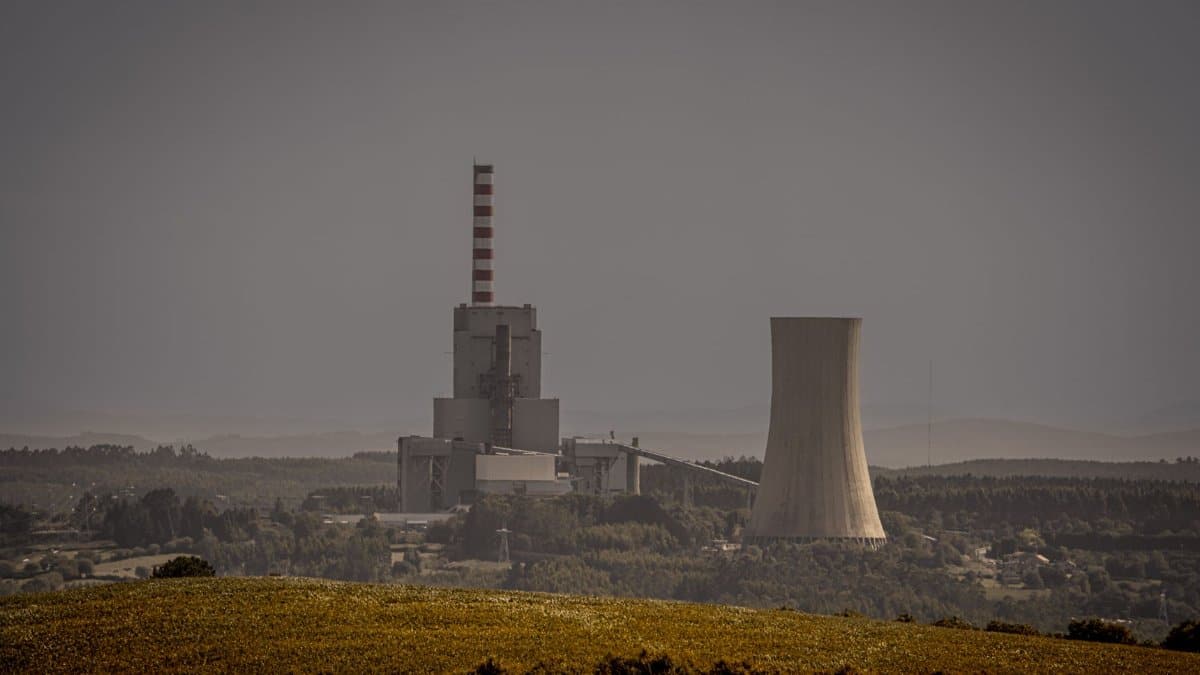 Distant view of a power plant with cooling towers amidst a vast landscape, illustrating energy production.
