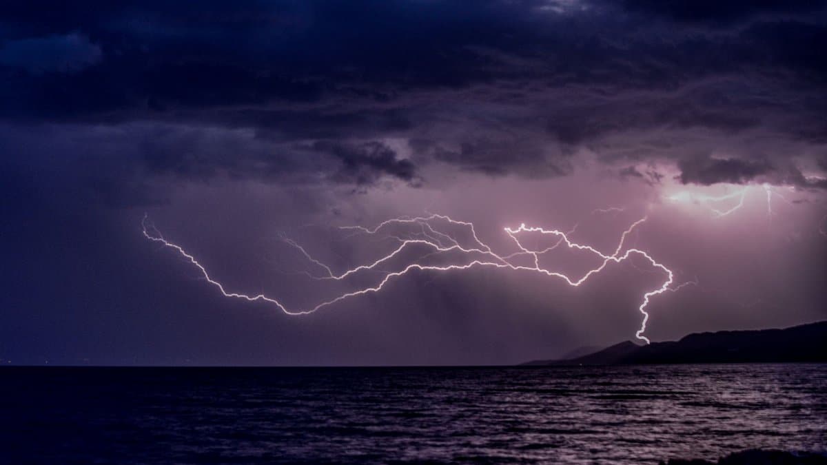 Vivid lightning bolt illuminating dark stormy clouds over a vast ocean, capturing nature's raw power.