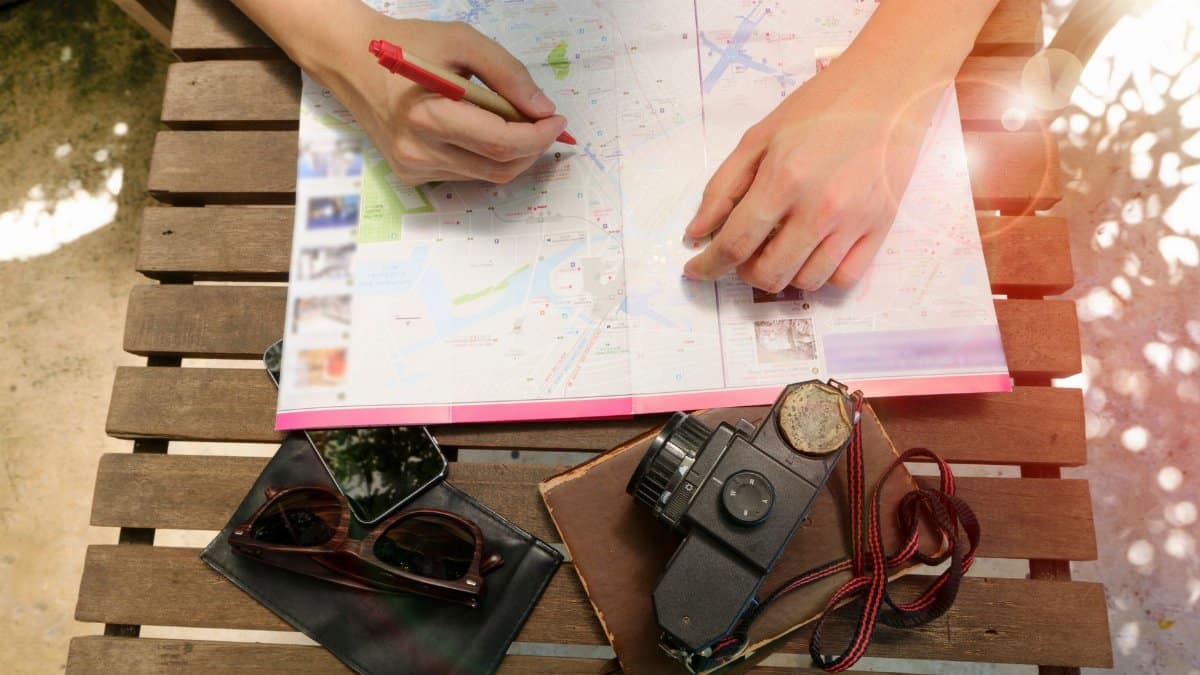 A person planning a journey using a map and vintage camera, evoking travel and exploration.