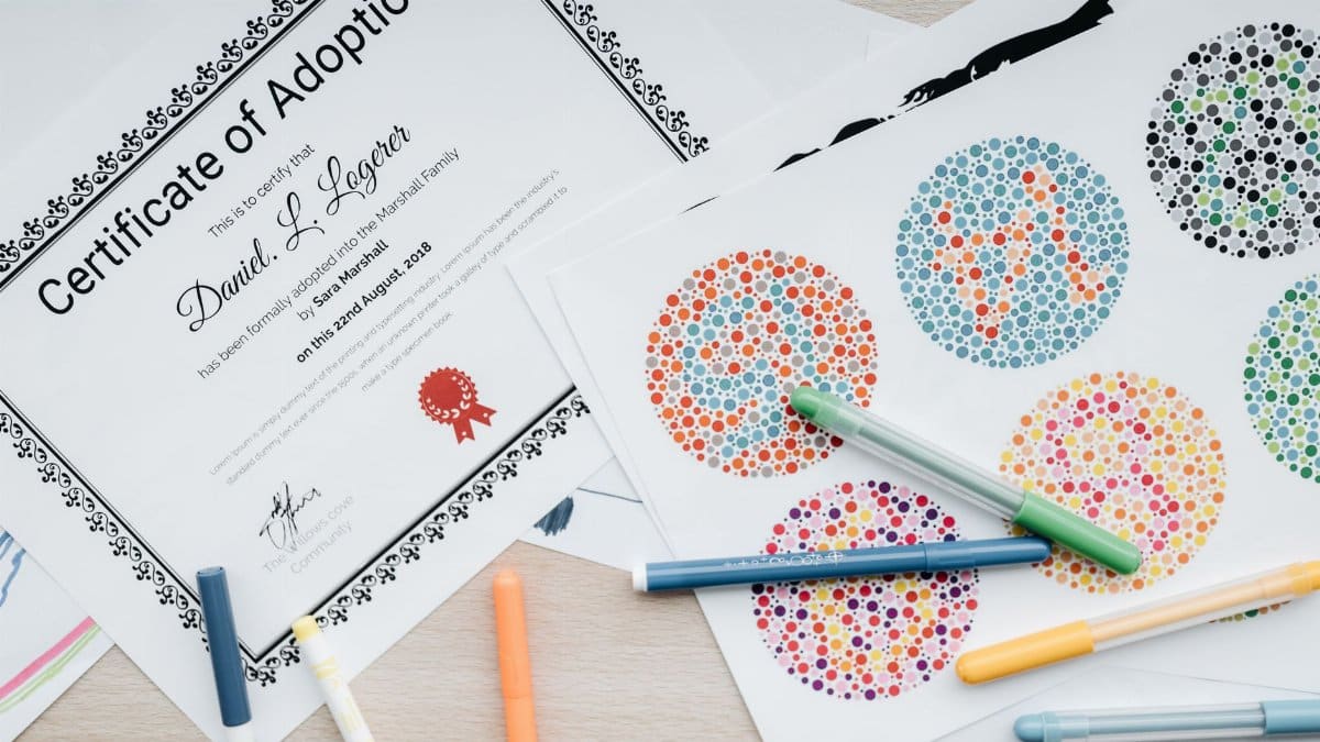 Adoption certificate surrounded by colorful pens and testing charts on a desk.