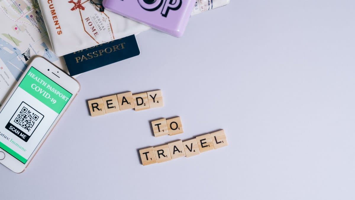 Travel essentials including passport, map, and health passport app ready for post-pandemic journeys.