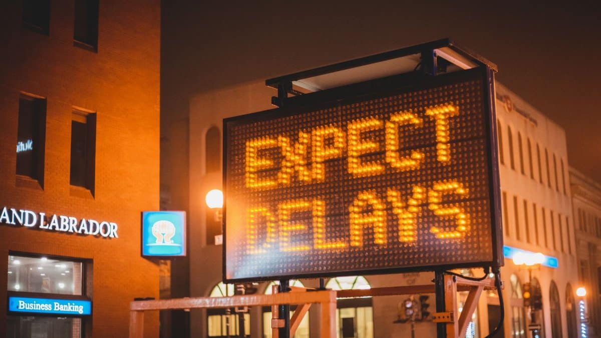 Mobile electronic traffic sign with inscription Expect delays placed on road in city street in evening time