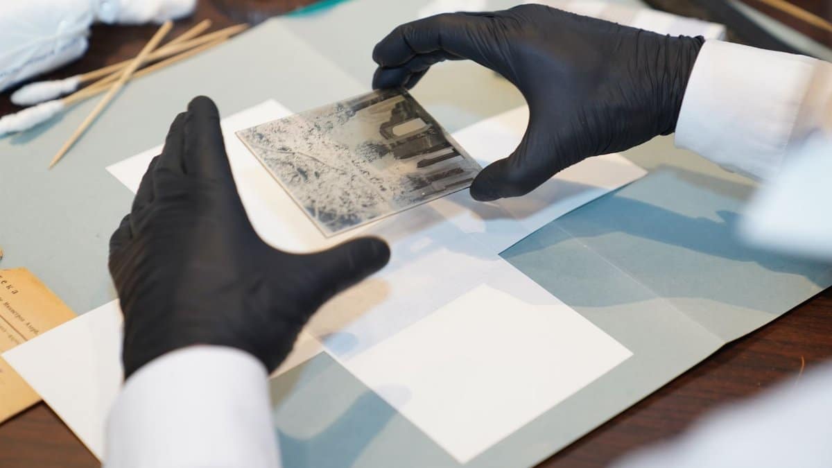 A specialist restoring an old photo using gloves and tools for careful preservation.