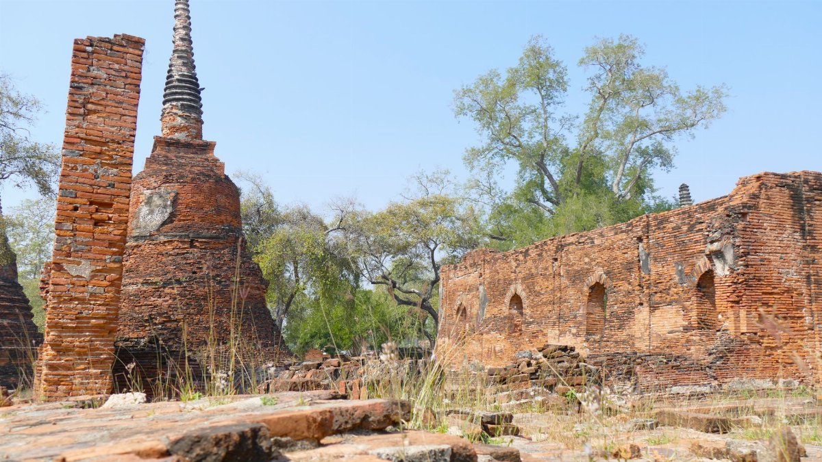 A serene view of historic brick ruins and pagoda under a clear blue sky, showcasing ancient architecture.