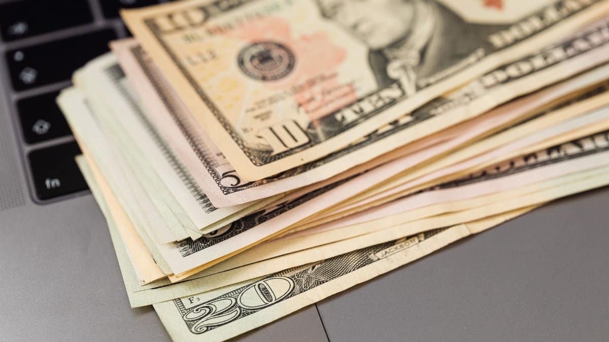 Stack of US dollar bills on a keyboard, symbolizing digital finance and wealth.