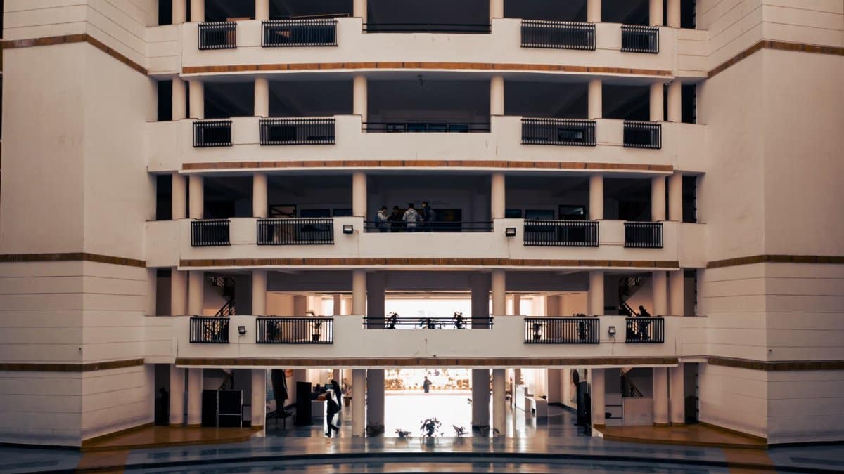 Wide view of a modern university building in Dehradun, India, highlighting architectural design and stairs.