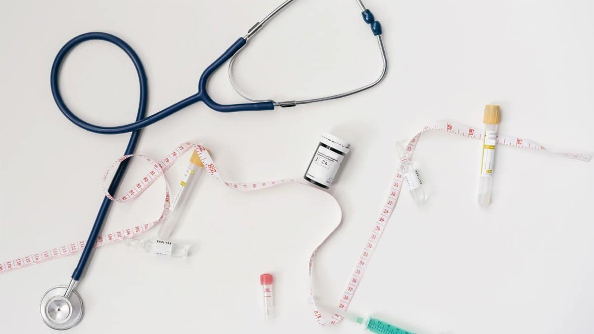 Top view of stethoscope, syringes, and tape measure on white background.