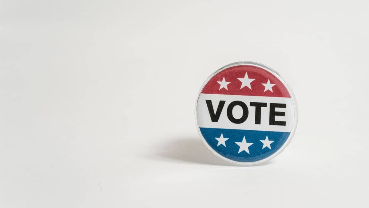 Close-up of a red, white, and blue vote button with stars on a white background.