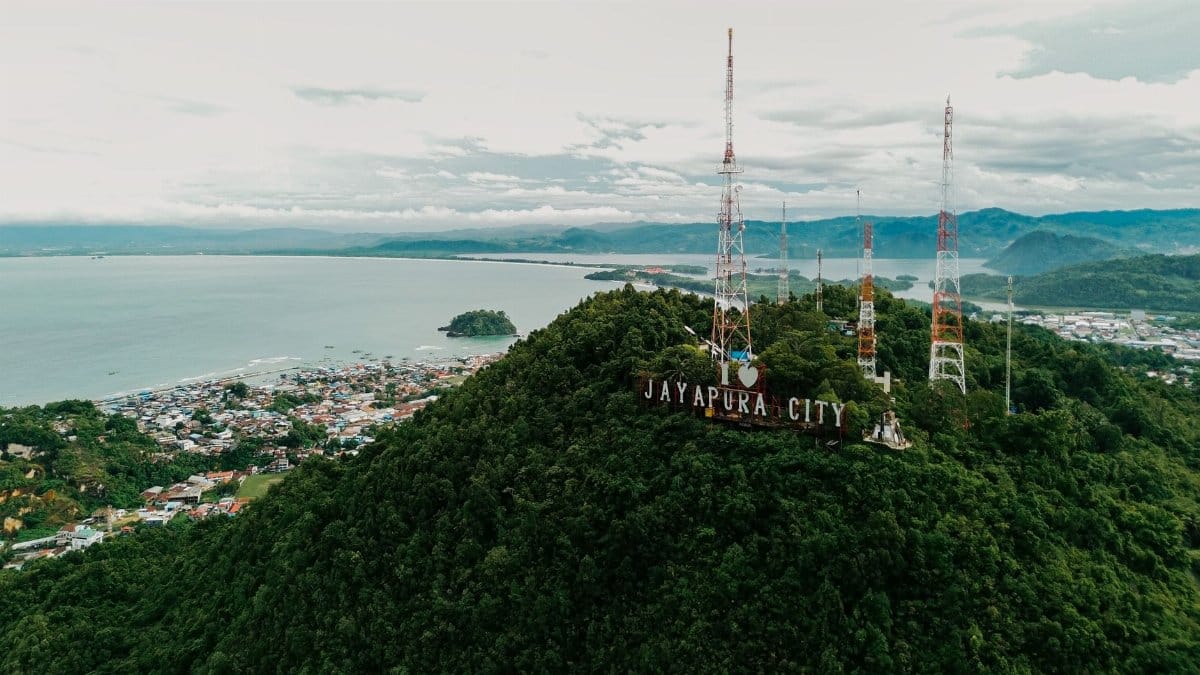 Stunning aerial view of Jayapura City with lush hills and ocean in Papua, Indonesia.