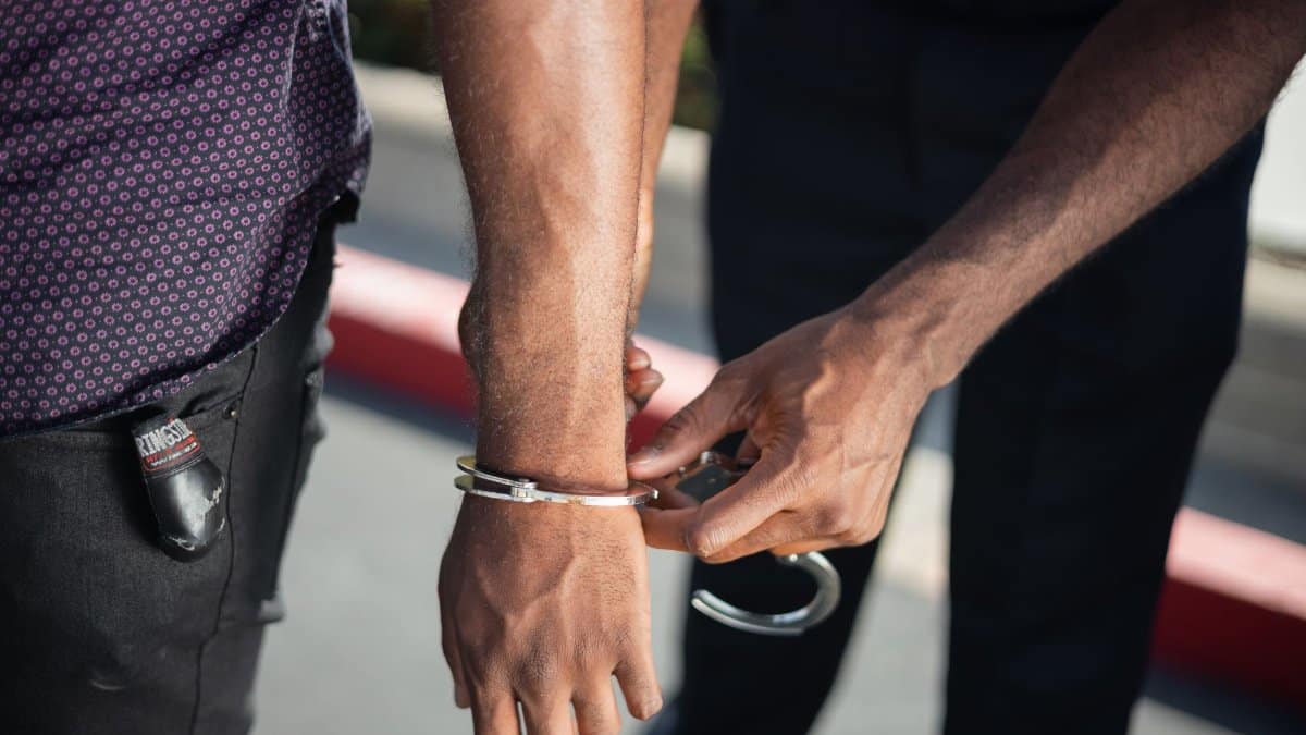 Close-up of a police officer handcuffing a suspect outdoors, enforcing law.