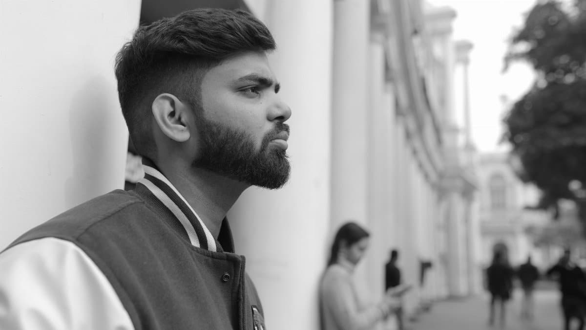 Profile of a pensive young man leaning against a wall outdoors, creating a reflective urban mood.