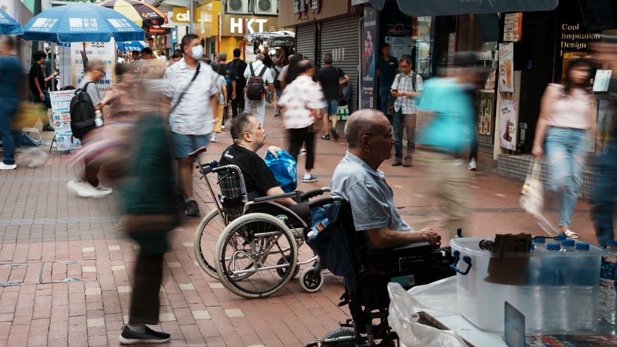 Vibrant city street with wheelchair users and fast-moving shoppers, capturing urban life.
