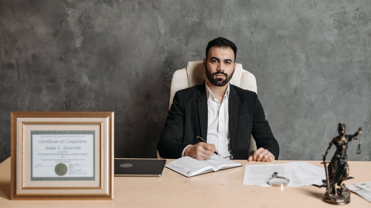Confident man sitting at a desk surrounded by legal documents and a certificate.