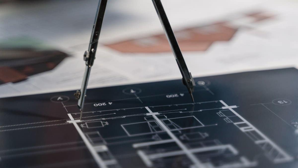 A compass on architectural blueprints, showcasing planning and measurement details.