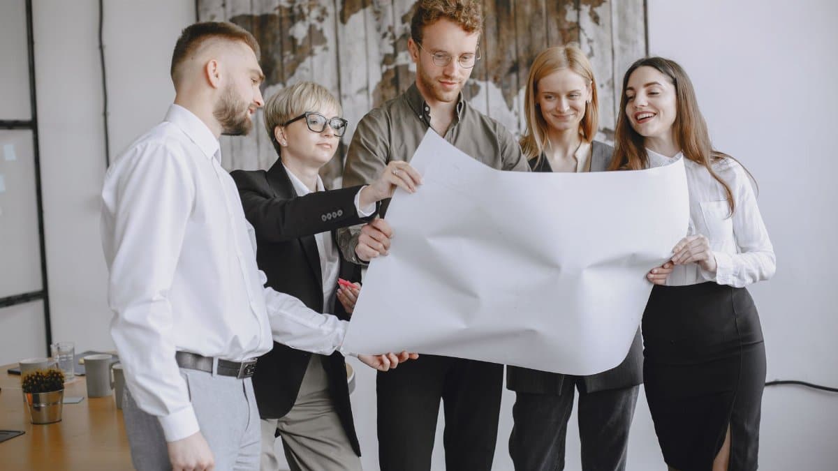 Group of professionals in an office setting analyzing project plans together.