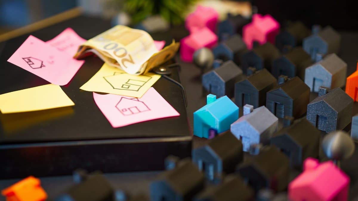 Colorful model houses next to Euro notes and sketches, showcasing real estate investment planning.