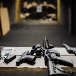 A selection of firearms and safety gear on a table at an indoor shooting range.