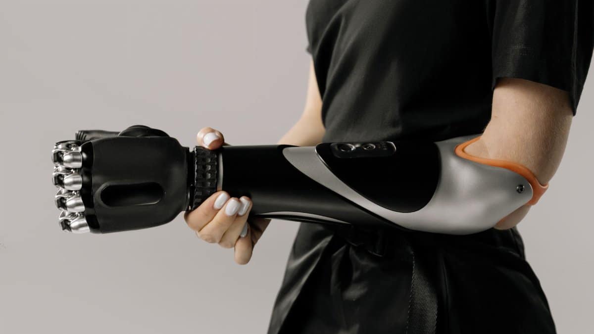 Close-up of a woman holding a sleek black prosthetic arm in a studio setting.