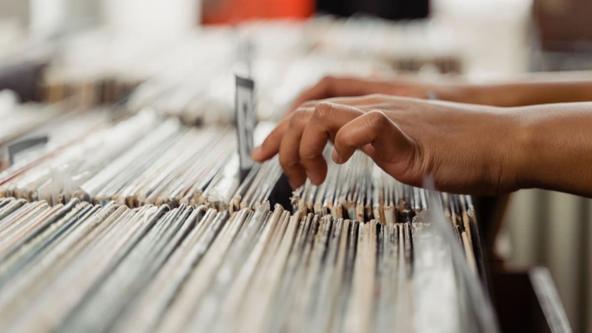 Close-up of hands searching through vinyl records, depicting a personal music shopping experience.