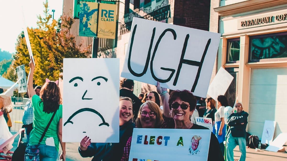 Lively street protest in Wheeling, WV with people holding creative signs and posters.