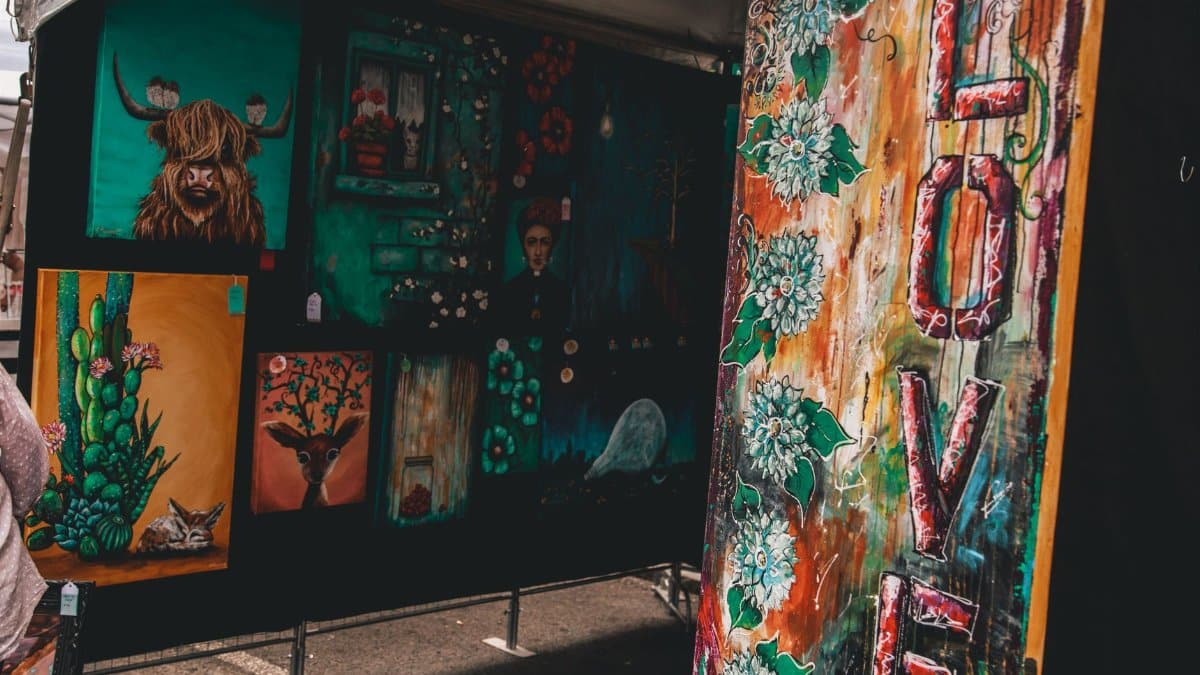 Colorful display of diverse artworks at an outdoor art fair highlighting contemporary styles.