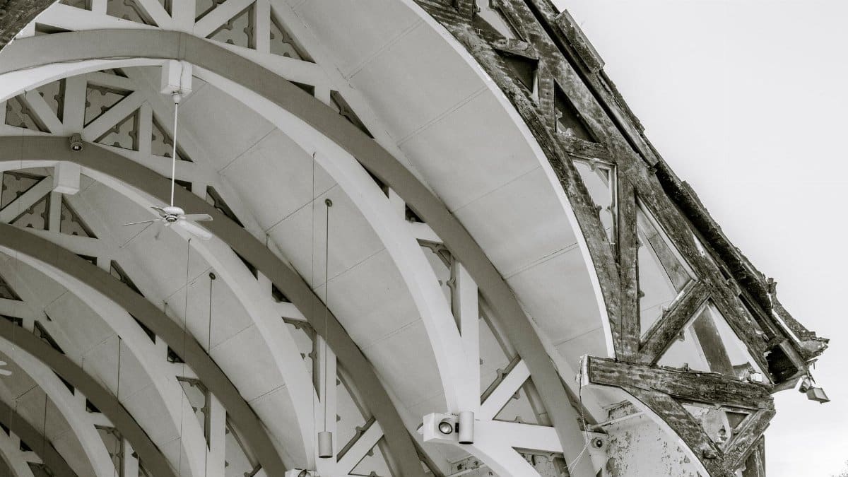 Grayscale photograph of an intricate arched ceiling structure with wooden and concrete beams.