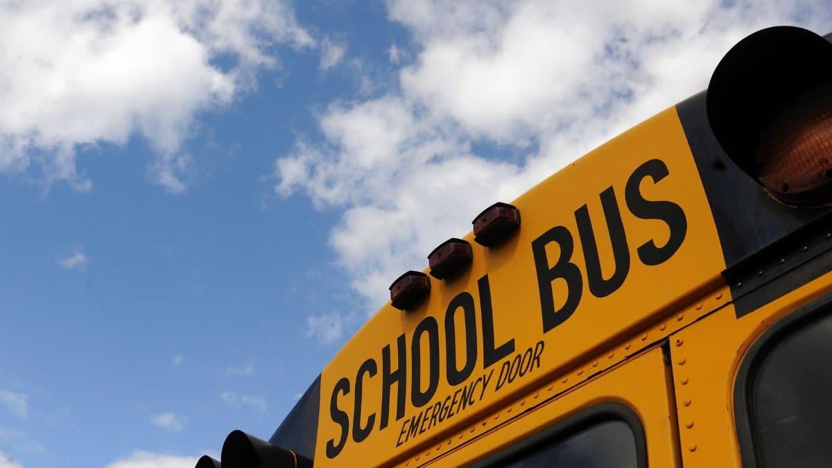 Close-up shot of a yellow school bus with a blue sky background, showcasing cloud formations.