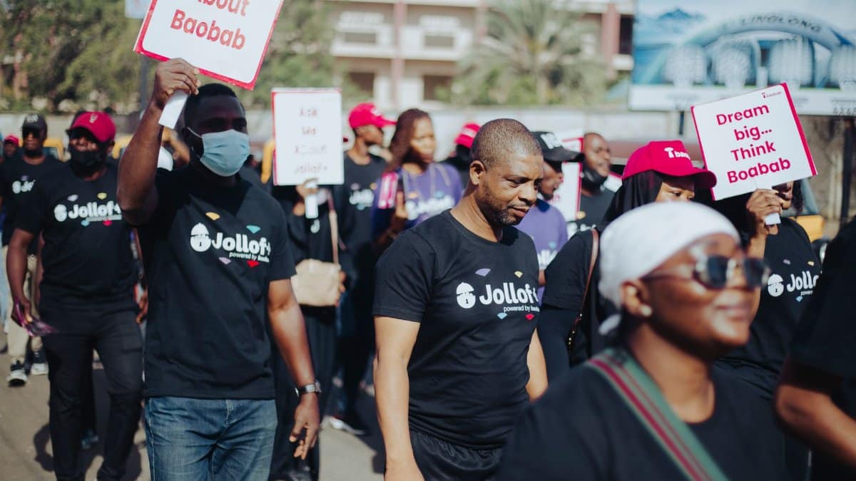 A group participating in a community walk for Baobab awareness, carrying signs.