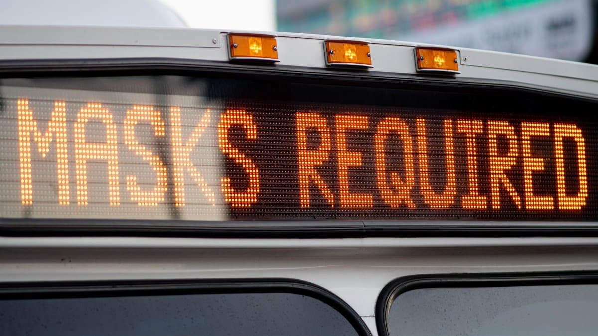 Close-up of a bus display sign showing 'Masks Required' for COVID-19 public transportation safety.