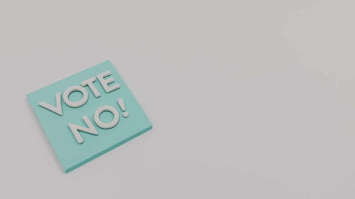 A blue sticky note displaying the message 'Vote No!' on a white surface, minimalistic and impactful.