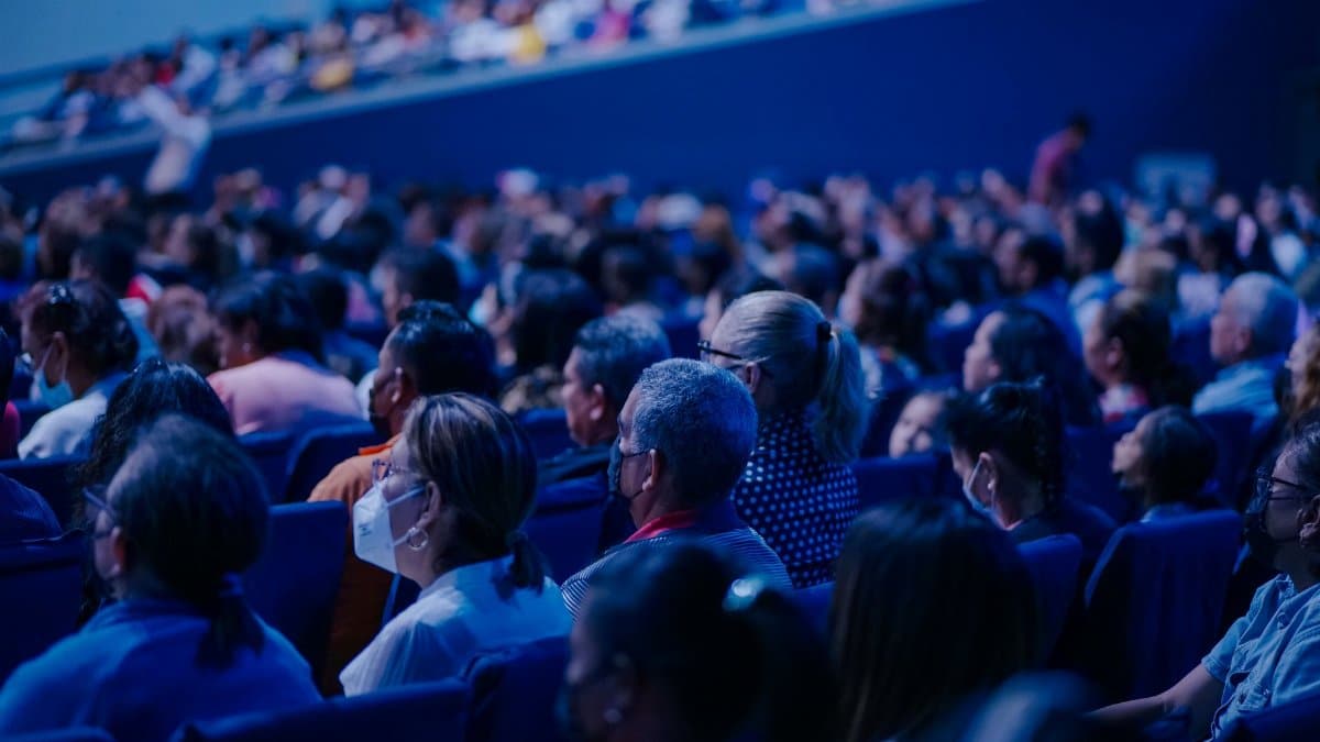 Diverse audience sitting in rows, attending an indoor conference or event.
