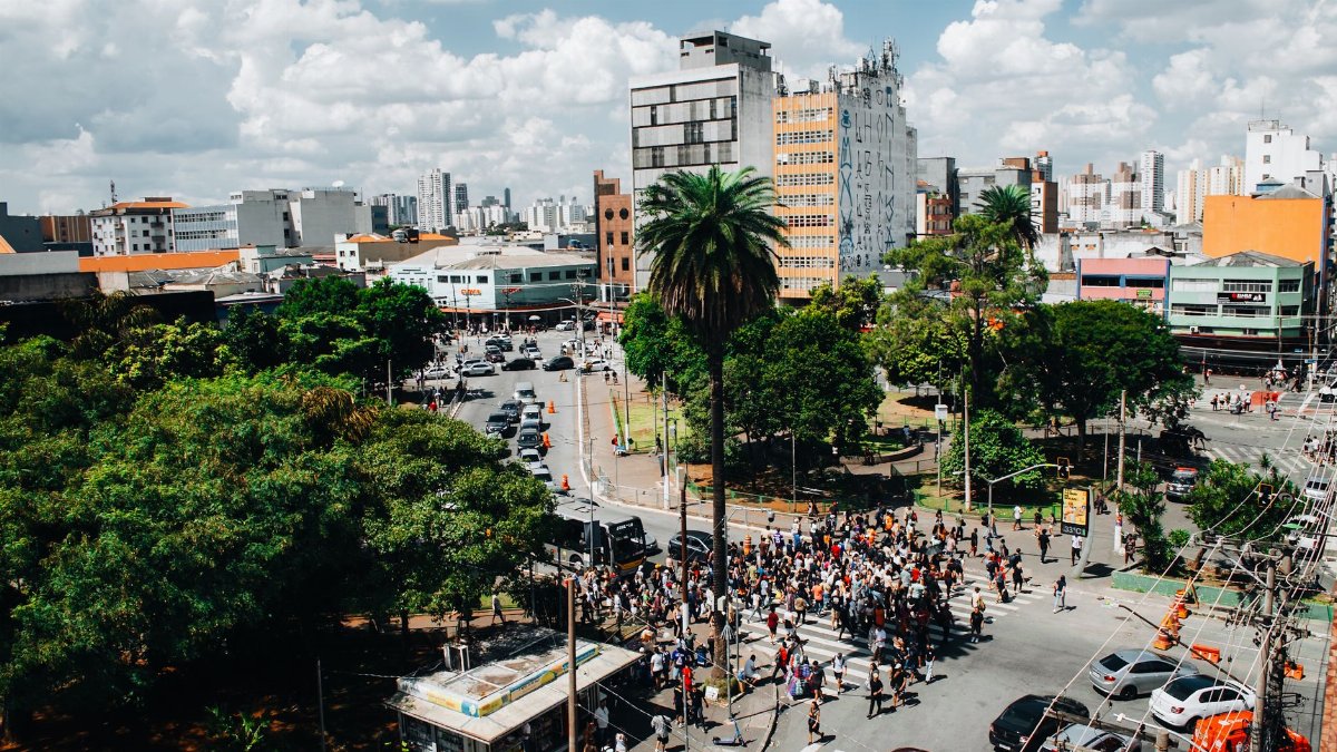 Aerial view of a busy urban intersection filled with people crossing the street under a clear sky.