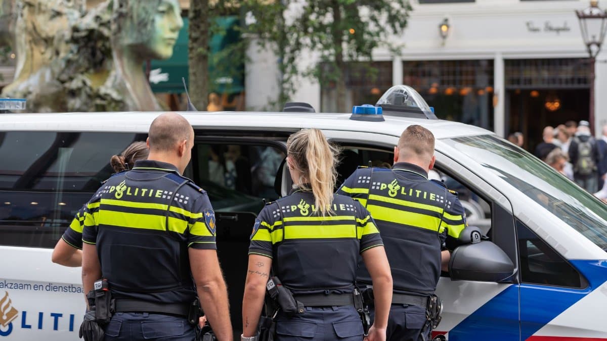 Police officers in uniform inspecting a vehicle on a busy city street, ensuring public safety.