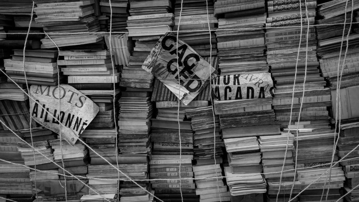 A monochrome photo showcasing stacked books tied with strings, conveying abundance and organization.