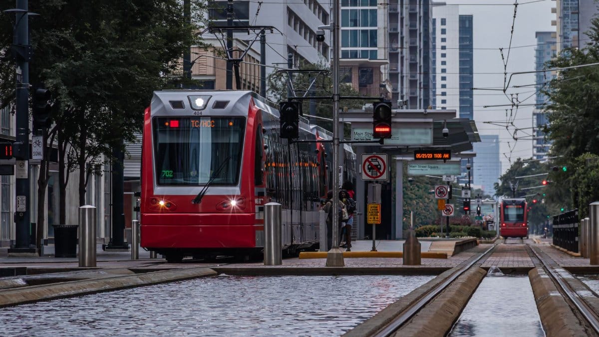 A modern red train travels along Main Street in downtown Houston, Texas.