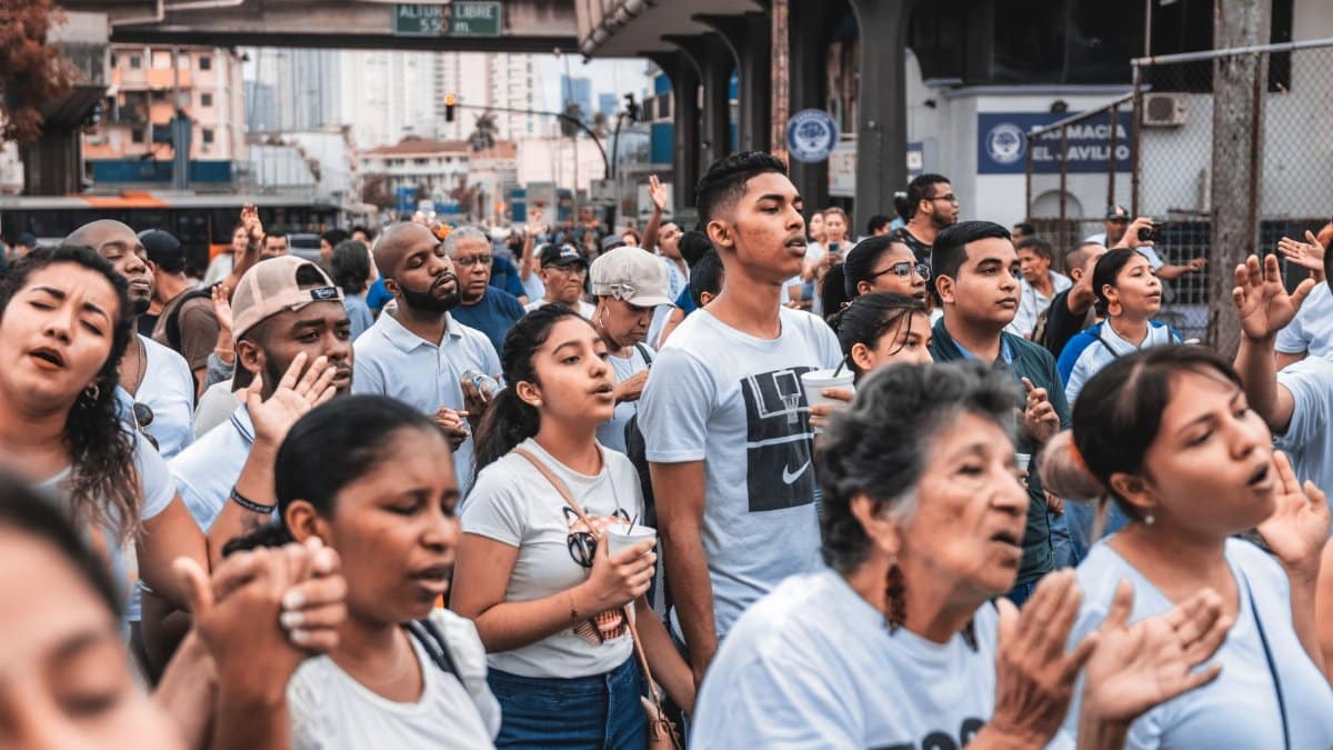 A large group of diverse people gathered outdoors, engaging in a community event in an urban setting.