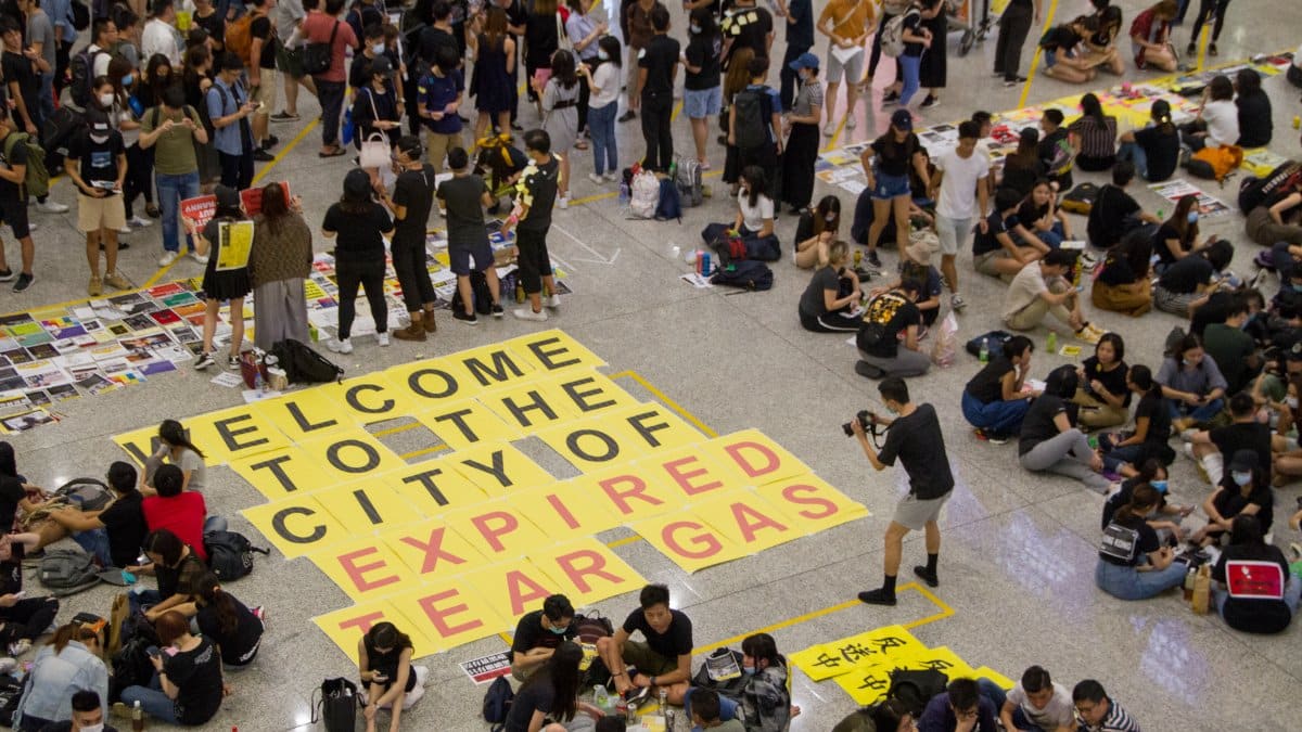 People gathered in a public space during a protest with prominent signage on the floor.