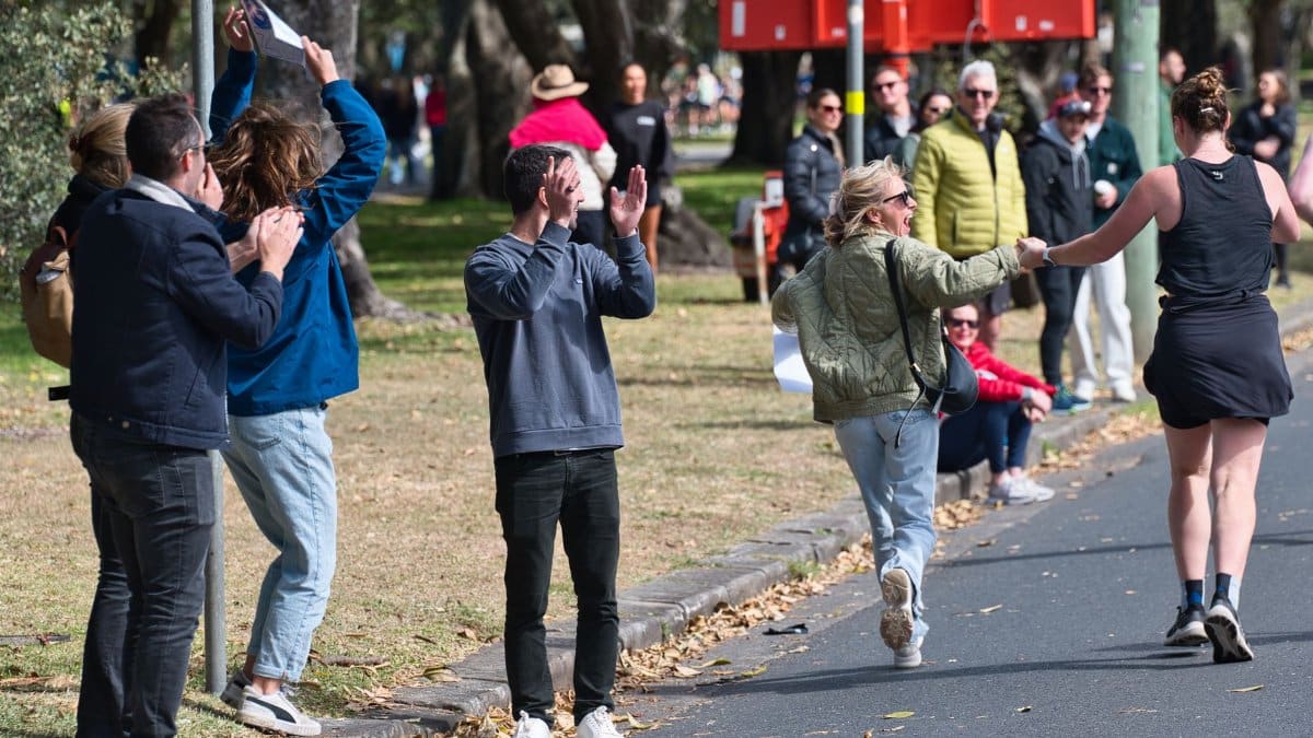 A joyful audience cheers on marathon runners in Sydney, capturing the city's vibrant atmosphere.