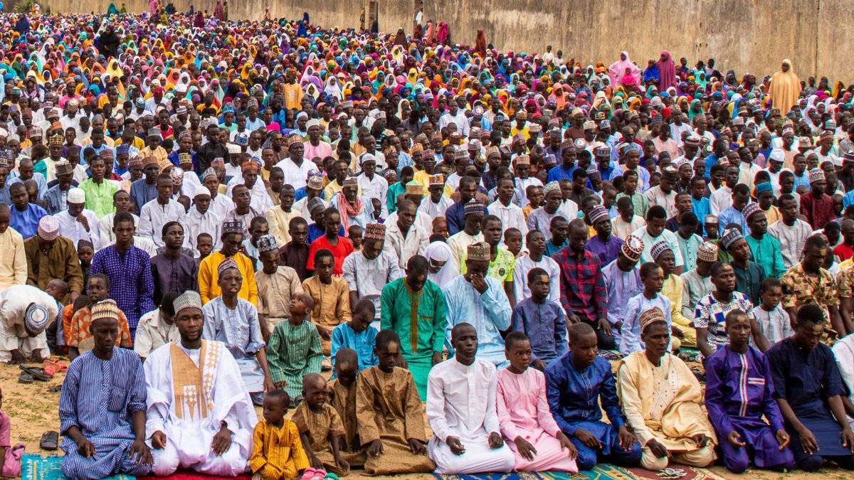 A vibrant outdoor prayer gathering with diverse participants in colorful attire in Maiduguri, Nigeria.